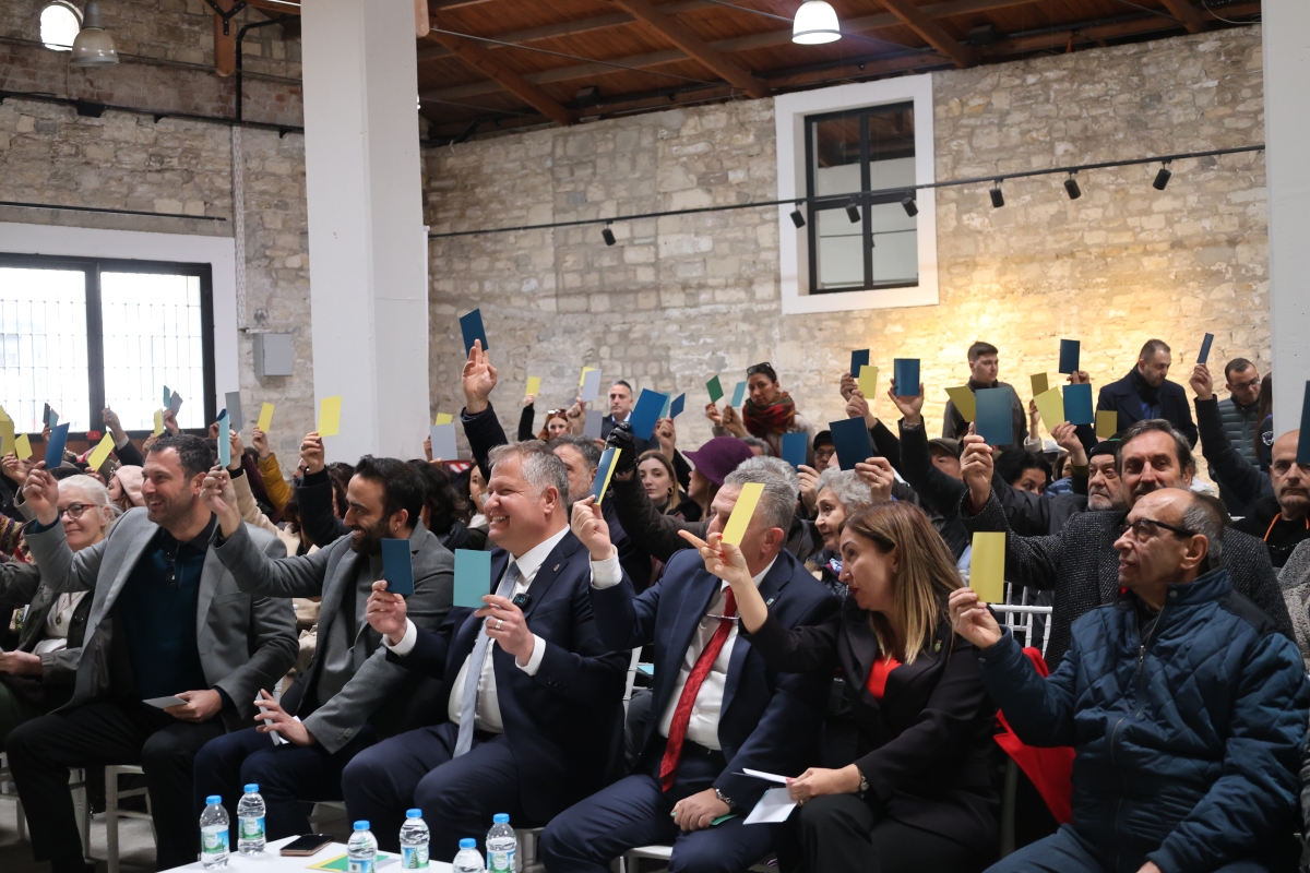 Panelde vatandaşlar ellerindeki farklı renklerdeki kartları kaldırarak tasarımları oylarken görülüyor